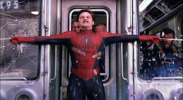 Spiderman straining with his arms stretched wide, trying to stop a train