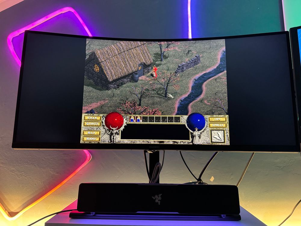 a 34" monitor with a razer speaker and some rgb leds in the back displaying the opening scene of Diablo 1