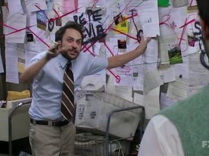 Charlie day in front of a wall covered in papers connected by red marks. 