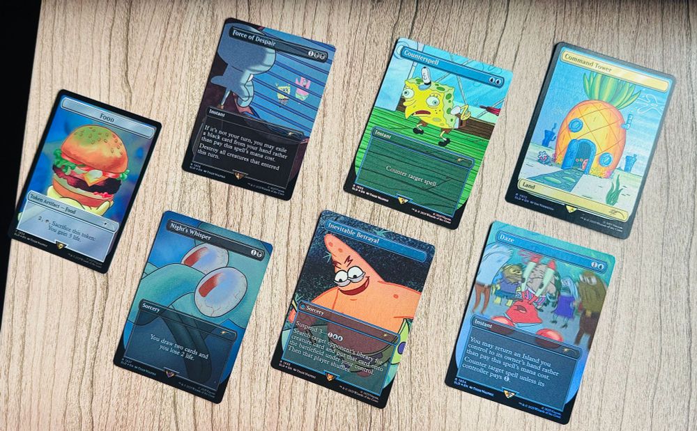 Seven Magic the Gathering cards on a table in rainbow foil treatment from Secret Lair's newest launch in partnership with Spongebob. Cards are: "Food" as a token artifact card that reads "Sacrifice this token: You gain 3 life. "Force of Despair" If it's not your turn, you may exile a black card from your hand rather than pay this spells' mana cost. Destroy all creatures that entered this turn. "Counterspell" Counter target spell. "Command Tower" land card, "Night's Whisper" You draw two card and lose 2 life. "Inevitable Betrayal" Suspend 3. Search target opponet's library for a creature card and put that card onto the battlefield under your control. Then that player shuffles. "Daze" You may return an Island you control to its owner's hand rather than pay this spell's mana cost. Counter target spell unless its controller pays 1.