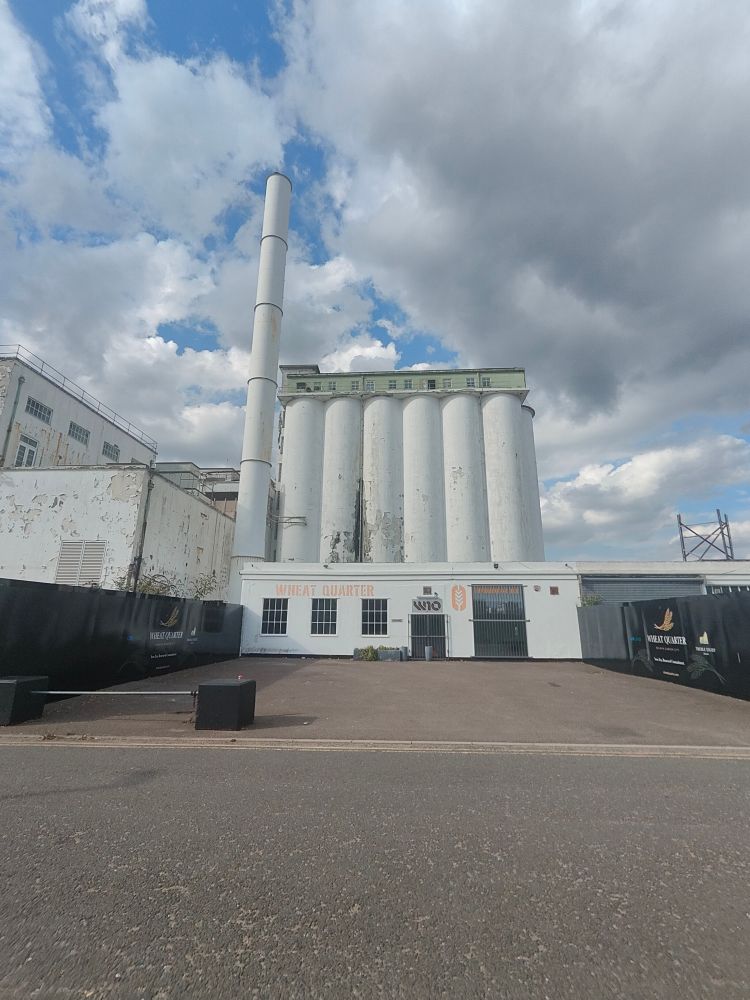 The former Shredded Wheat factory in Welwyn Garden City. White painted concrete silos and a tall chimney.