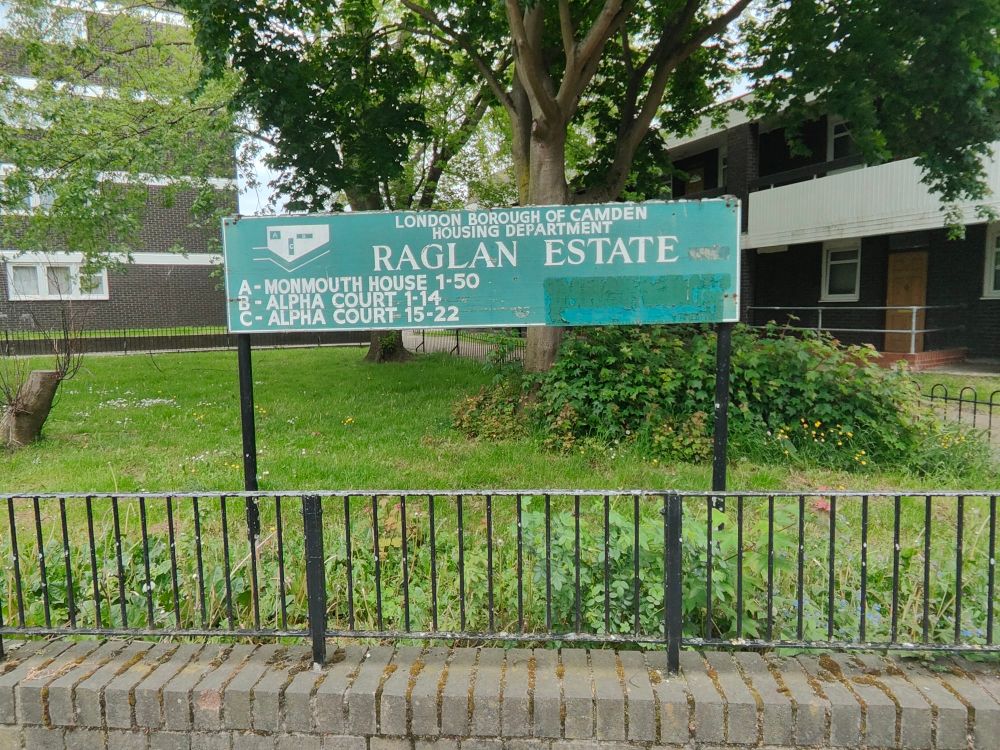 Large painted wooden sign, white on green:
LONDON BOROUGH OF CAMDEN 
RAGLAN ESTATE 
Simple map on left side, with key below 