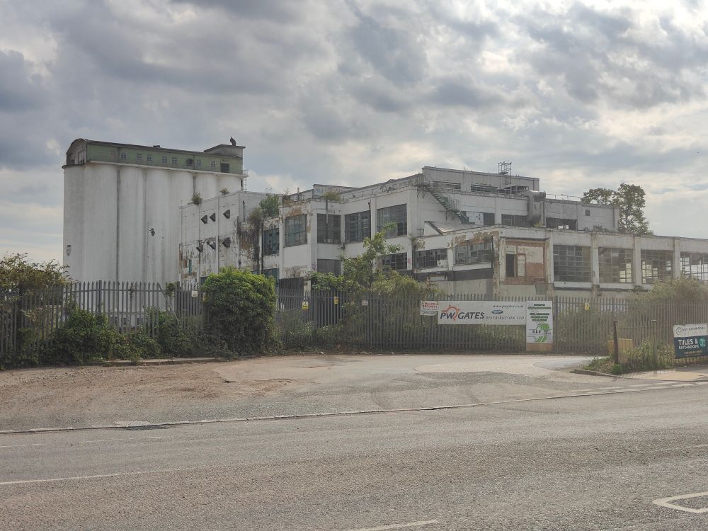 The former Shredded Wheat factory in Welwyn Garden City. White painted concrete silos, partially demolished production building in front.