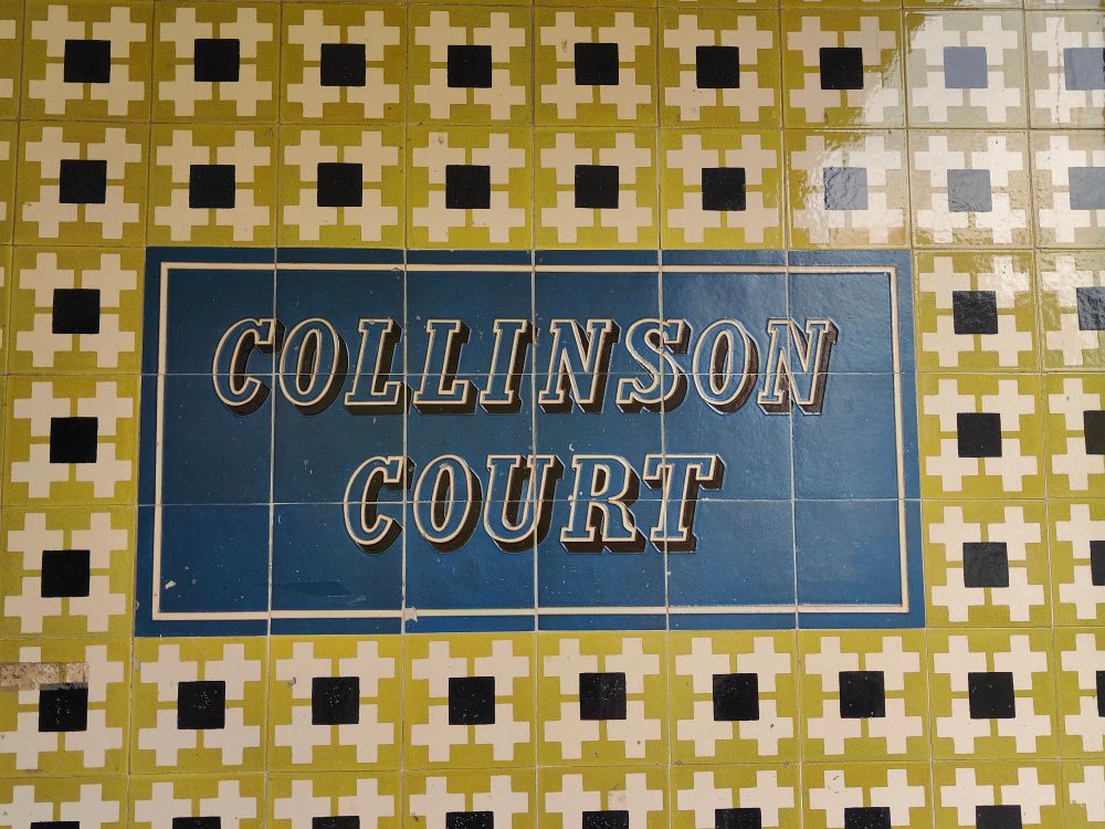 COLLINSON COURT tiled sign. Yellow on blue, surrounded by yellow, black and white patterns in Festival of Britain style