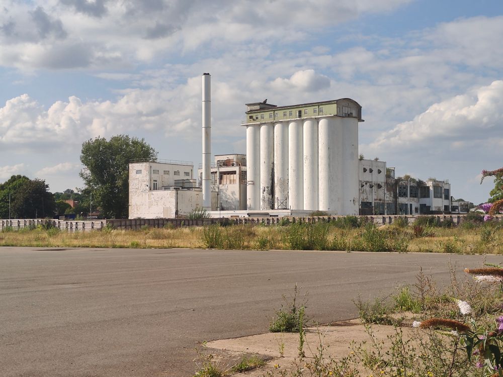 The former Shredded Wheat factory in Welwyn Garden City. White painted concrete silos and a tall chimney.