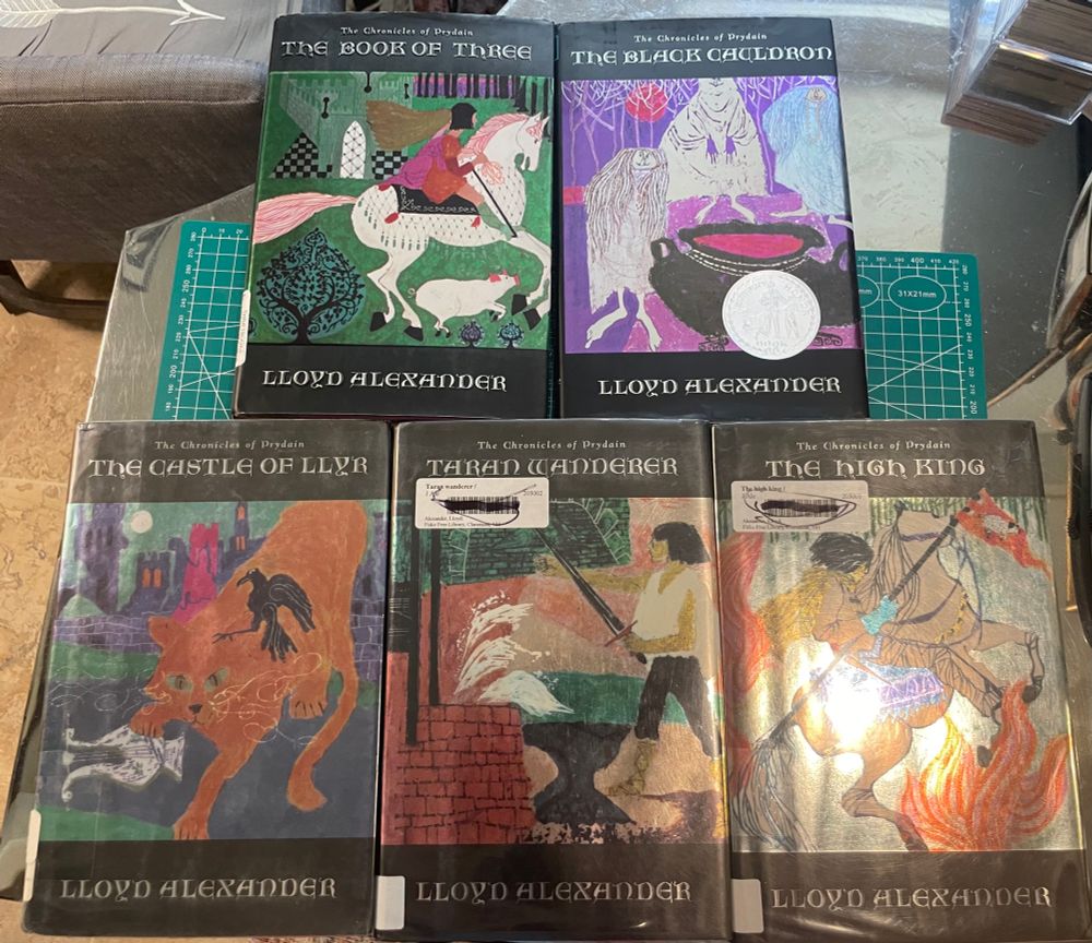 Five hardcover books, the Chronicles of Prydain, with black trim and silver lettering, and center dust jacket art by Evaline Ness.