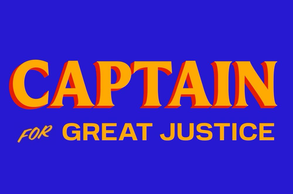 On a blue background in orange letters, with drop shadow left in red, top line in larger font, lower line in smaller font, the text is “Captain for Great Justice”