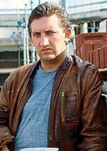Jimmy Nail as Oz Osbourne from Auf Widersehen Pet in brown leather bomber jacket and chambray blue tee, looking confused as he tries to decipher this pun 