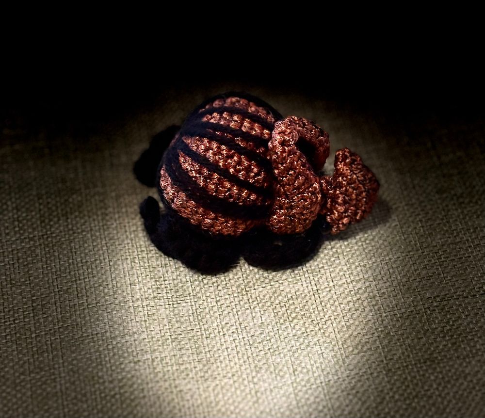 A crocheted, bronze/rust-colored beetle