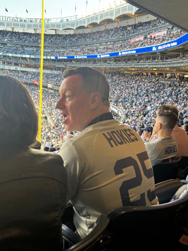 A man in a Yankees-themed Virginia Tech jersey speaks.
