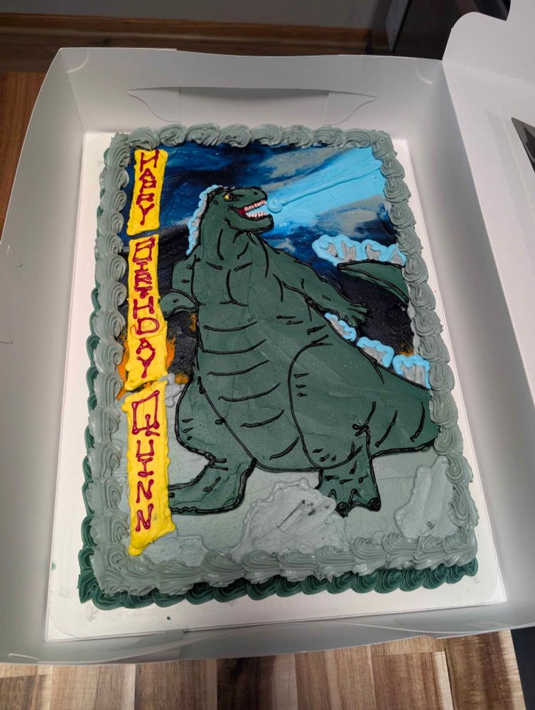A birthday cake with a Godzilla design on it.