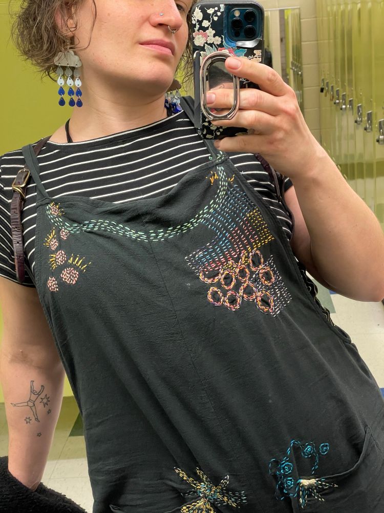 locker room mirror selfie featuring my favorite 🌧️ earrings joined by ⛈️, etc stitching on my jumper 