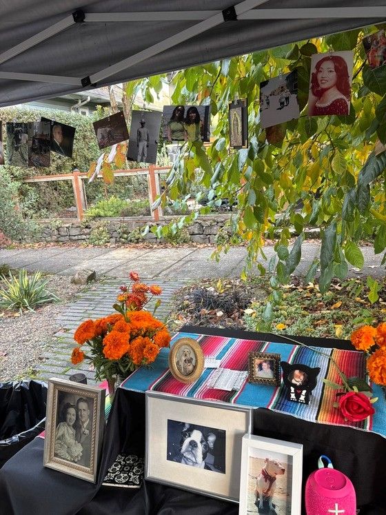 A Dia de Los Muertos ofrenda table has framed pictures, marigolds, and a colorful tablecloth. Photo credit: Kenneth Walton, Concordia Neighborhood.