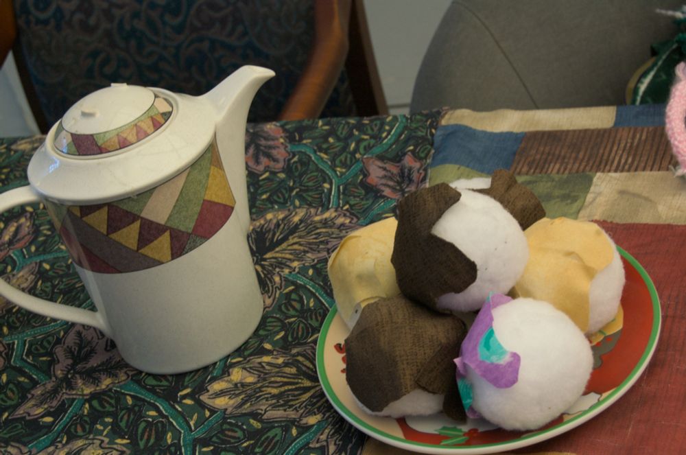A tea pot and a plate of round, white, cake-like balls.