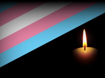 a trans flag and a lit candle on a black background
