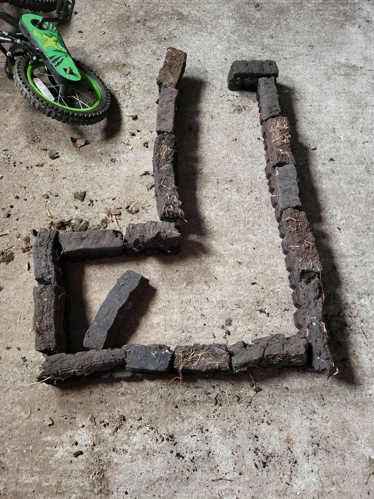 A child's creation of a house built with sods of turf and peat briquettes 
