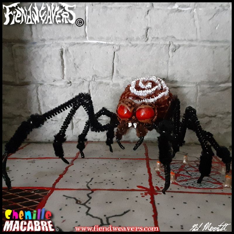 A pipe cleaner figure I built of a spider I call the Spiral Deathtrap. She is a brown spider with black legs and large sinister red eyes. Her bulbous abdomen bears a white concentric spiral pattern above her head. Her four forelegs are much longer than her four hind legs and they all end in black claws.