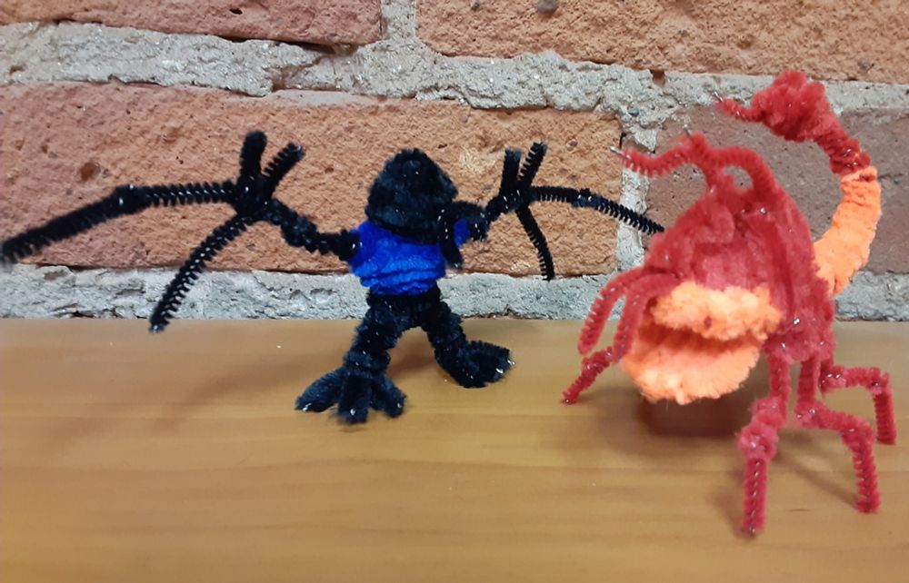 Two pipe cleaner figures I am currently building. The first is a black featureless Mothman with pterodactyl-like wing fingers and a blue chest. The second is a Thorwor, a red monster with a reptilian head, arthropod legs, and tail stinger. Each stands 2" (5.08 cm) high.