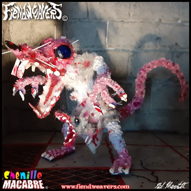 A pipe cleaner figure I built of Thrush, a playable character in my tabletop fighting game AMPUTHEATRE. Thrush is a giant marsupial rat with mangy gray fur, a bald head, dark blue eyes, and fangs dripping with blood. She stands on her hind legs and a baby rat snarls from her pouch. Thrush's head and arms are removable for AMPUTHEATRE combat, and she can eat the baby for health if necessary. She stands 3" (7.62 cm) high at the shoulder.