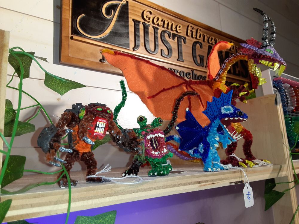 Pipe cleaner figures I built that are for sale at Dice Versa in Rochester, NY. From left to right: an Umber Hulk, a Neo Otyugh, a blue dragon, and a large orange dragon.
