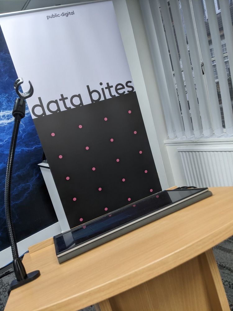 A banner - top half white with public•digital in small text at the top, data bites in large text right at the bottom; bottom half dark grey with rows and columns of pink dots - behind a pine lectern which has a screen resting on it and microphone holder

Ahead of tonight's Data Bites #50 event

https://www.eventbrite.co.uk/e/data-bites-50-tickets-1027991940567