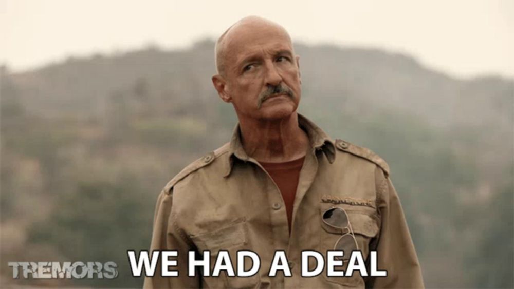 a man with a mustache says we had a deal in front of a mountain