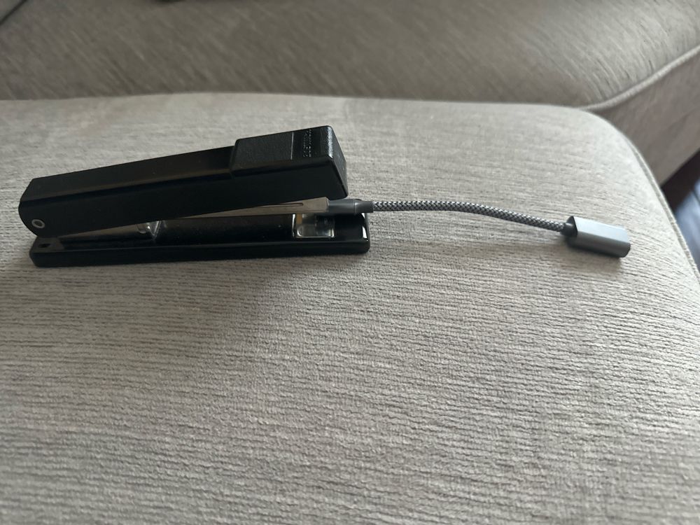 It’s an office stapler with a usb adapter cord hanging out of the mouth of the stapler