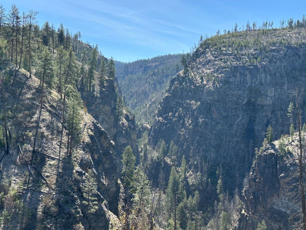Looking down a canyon with a river at the bottom and multiple levels of rock walls coming up on each side.