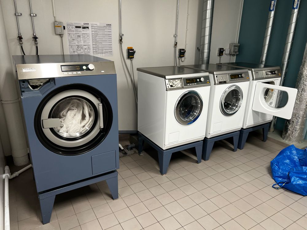 Stor blå tvättmaskin m.m. i en gemensam tvättstuga.