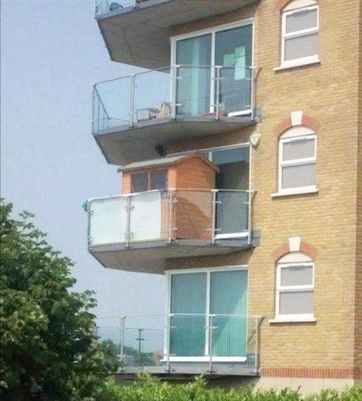 A block of flats showing one particular flat with a shed on the balcony.