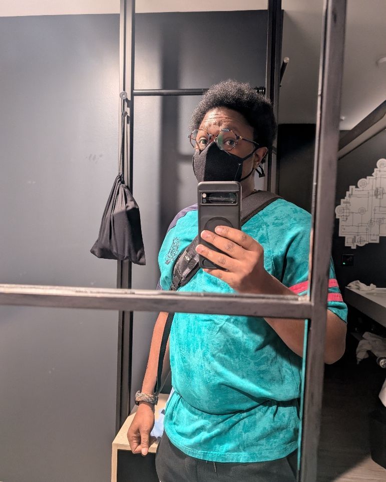 Sparrow wearing a teal shirt and a black mask, along with hexagon glasses. 