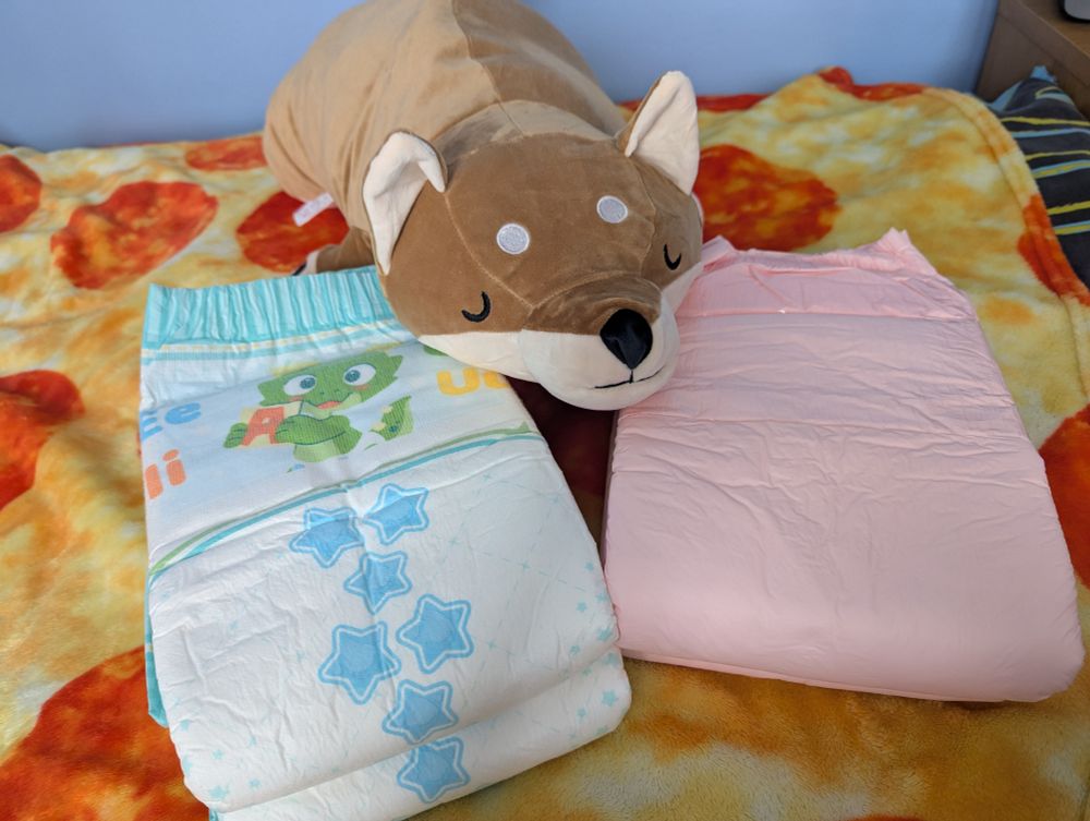 Samples of Trest and Try Again diapers with a sleepy shiba inu plush in between.