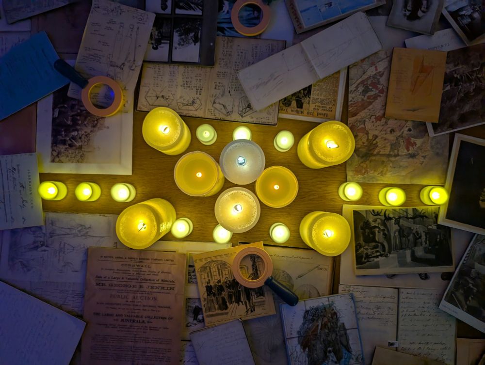 (Fake) candles and archive facsimiles on a table, including magnifying glasses.