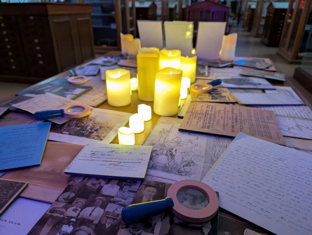 (Fake) candles and archive facsimiles on a table, including magnifying glasses.