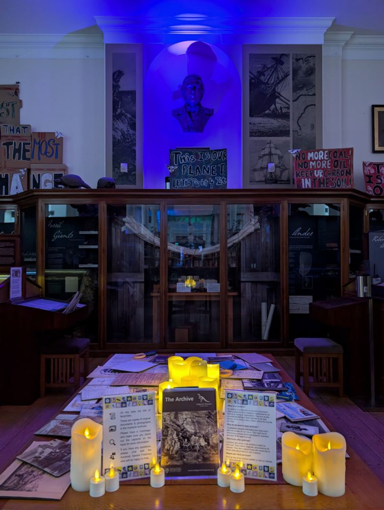 Darwin exhibition with a table of archive facsimiles and fake candles in front of it. 
