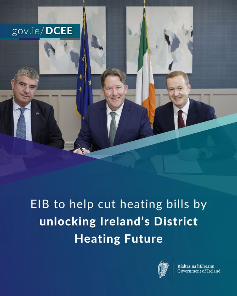 Three individuals pose behind a table with the Irish and EU flags in the background, representing an announcement by the European Investment Bank to support Ireland's district heating initiatives. The logo of Gov.ie/DCEE and "Rialtas na hÉireann Government of Ireland" are displayed.