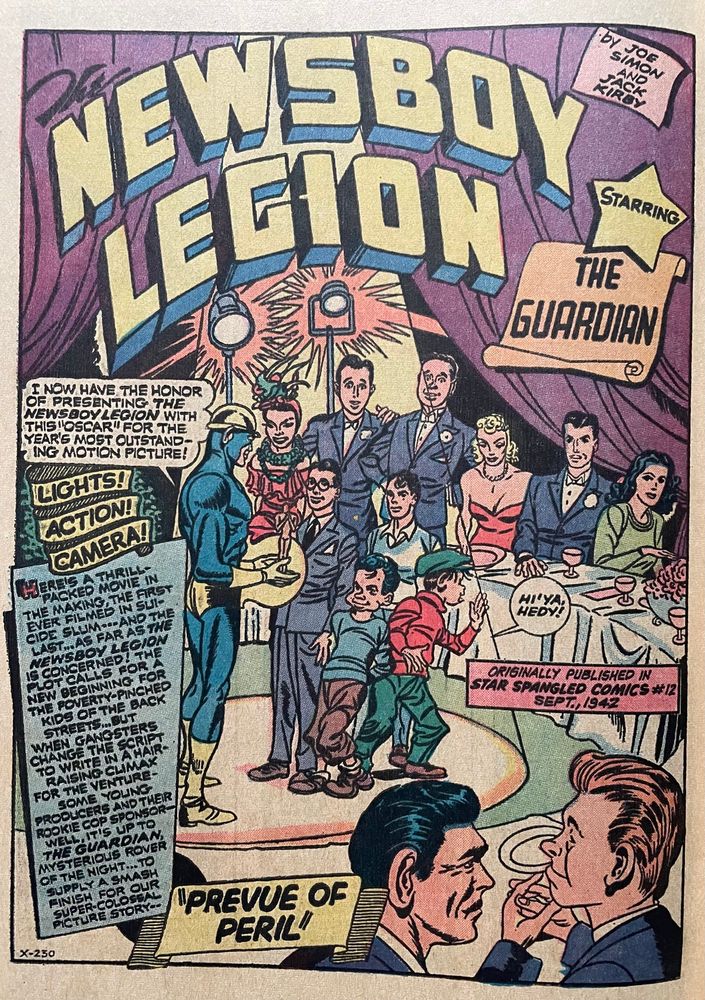 The Guardian and Newsboy Legion stand in the spotlight at a banquet surrounded by Hollywood stars. 