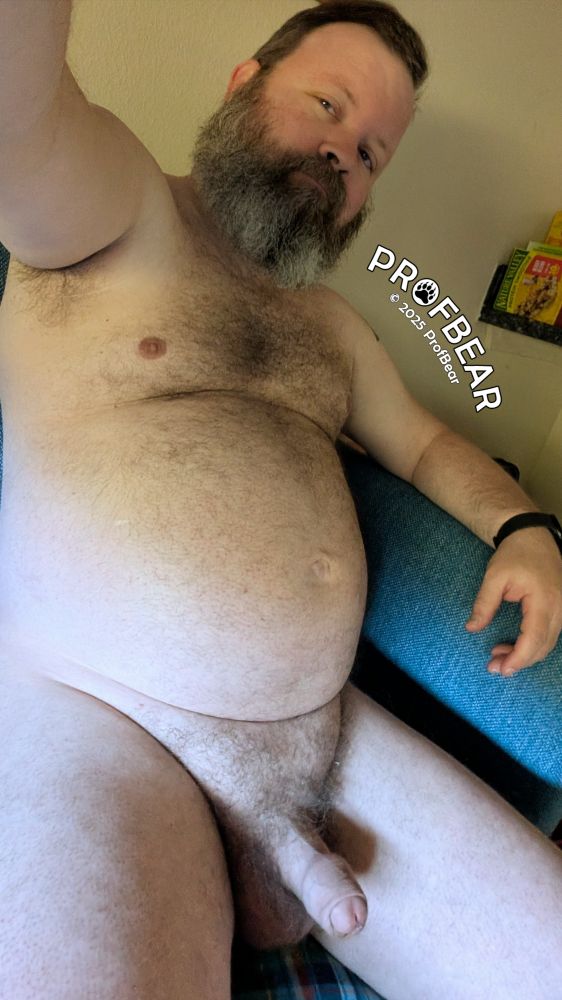 A naked, bearded CIS man on a couch.