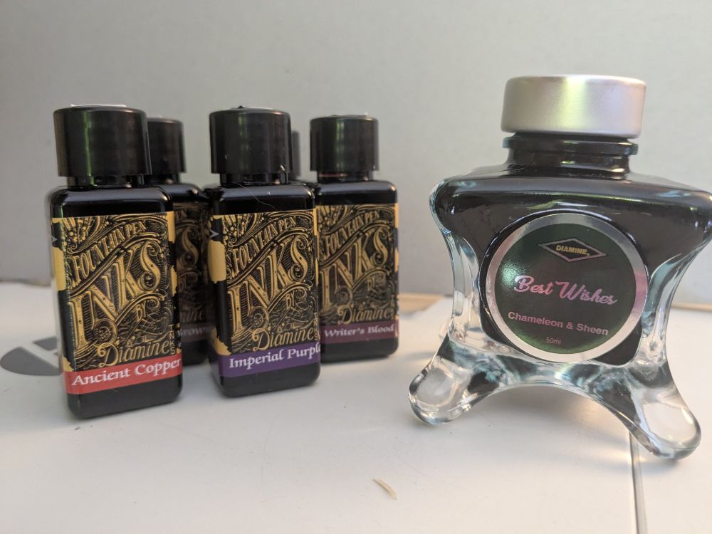 Some small rectangular Diamine ink bottles and an interesting-shaped glass bottle of dark green ink.