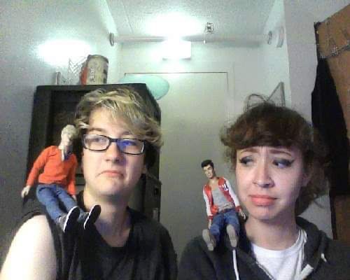 Freshman dorm MacBook selfie. My friend is frowning and has their sleeves rolled up with a Niall doll on their shoulder. I am wearing a hoodie and frowning at the zayn doll on my shoulder