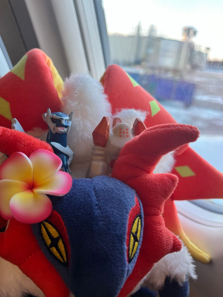 Slither wing plush with Dialga and Regirock figures by a plane window 