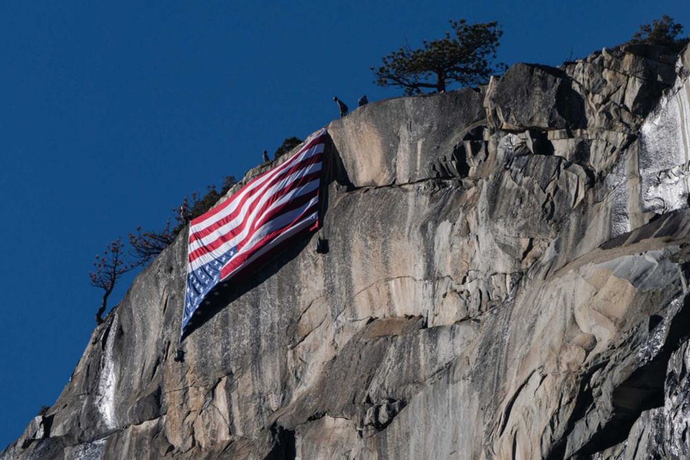 A US flag is positioned upside down, hanging on the face of El Capitan in Yosemite National Park.