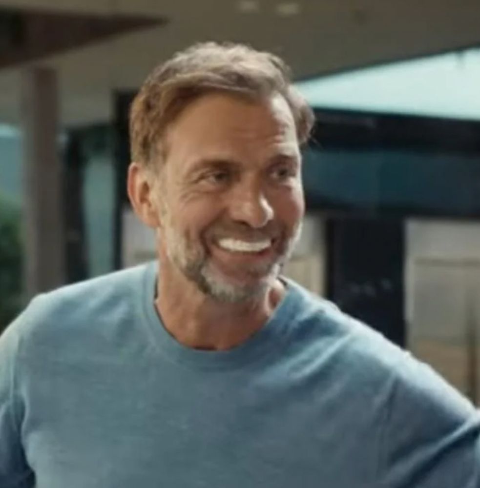 White man in a light blue crew neck sweater with abnormally large, unnaturally white teeth, 