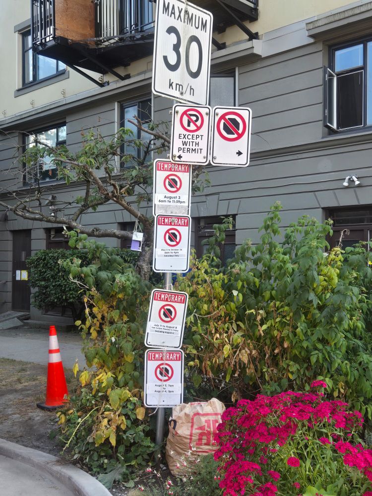 6 parking and stopping signs all on one pole with overlapping times and dates

