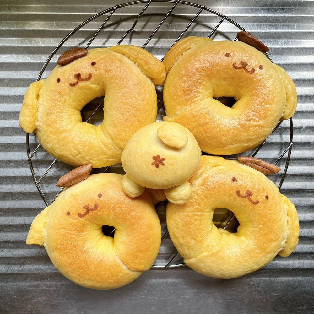 ポムポムプリンを模したベーグルです。潰したかぼちゃを練り込んでおり生地は薄い黄色、水溶きしたココアで顔を描いています。余った生地で作ったポムポムプリンのおしりもあります。