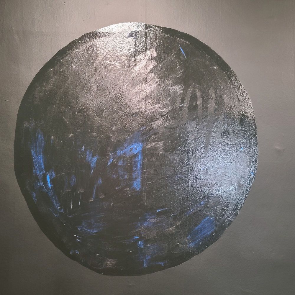 A shiny circle of gilding adhesive on a painted wall