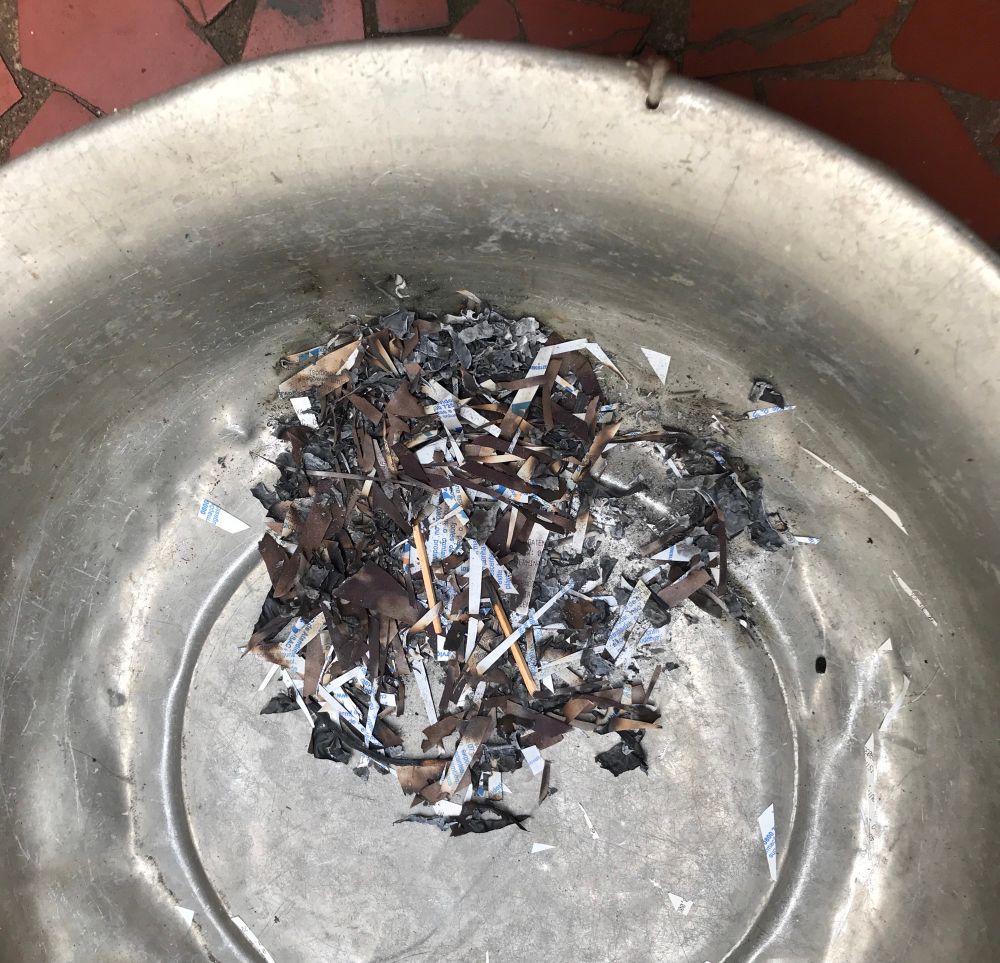 foto de uma bacia de metal com papel queimado dentro com uns palitos de fósforo compridos junto 