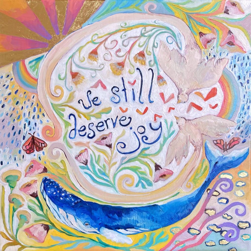 A colorful painting of birds, flowers, a whale, and rainbows with the words “we still deserve joy”.