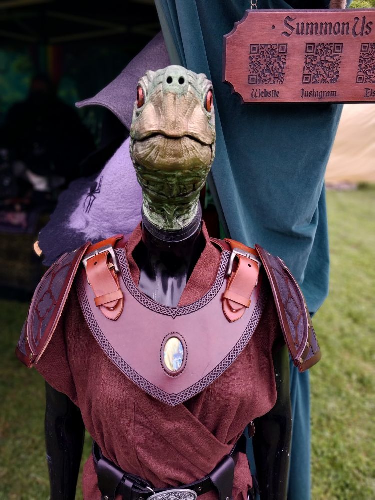 A front view of the turtle mannequin wearing a brown leather gorget with engraving and a labradorite stone