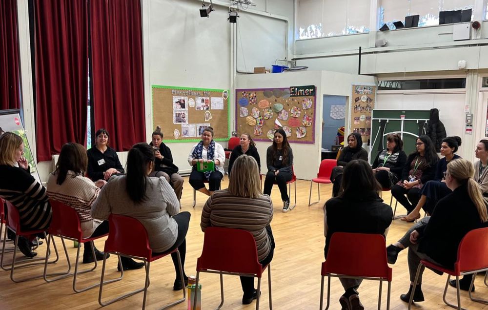 A group of teachers sitting on chairs in a circle formation at workshop